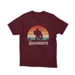 A Maroon tee with a 'Bassquatch' playing the guitar, from Apparel by Cetakshop, for those who believe in the beat.