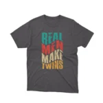 A playful 'Real Men Make Twins' slogan on a dark heather graphic tee from Apparel by Cetakshop, ideal for dads with a sense of humor.